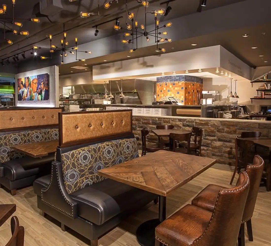 Luxury leather booth seating with industrial light fixtures and a clear view of the open stone-brick kitchen area at J. Baldwin's Restaurant.